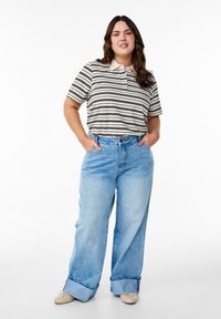 Polo à rayures en crème et bleu marine, assorti à un jean large taille haute bleu clair, avec des ourlets retroussés et une coupe décontractée.