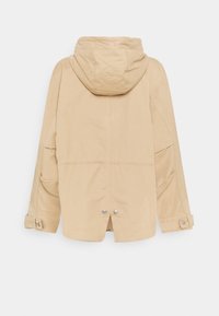 Beige vandtæt jakke med hætte, elastisk talje og trykknapmanchetter; har en afslappet pasform og sidelommer.