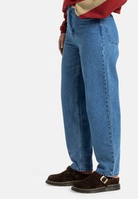 Højtaljede, lige ben blå jeans lavet af denim med en let falmning. Bæres med brune ruskind slip-on sko.