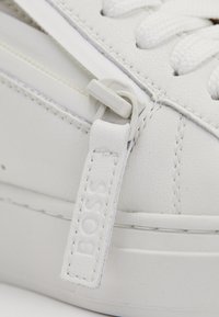 Hvide lædersneakers med stitched detaljer, en glat overflade, rund form og en brandet snøretrækstabs for nem påtagning.