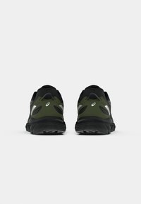 Chaussures de sport noires et vert olive avec une tige en maille texturée, des accents réfléchissants et une semelle noire durable. La vue de dos montre un design épuré.