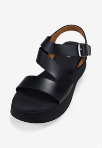 Sandalias negras con tres bandas anchas, una hebilla y una suela de plataforma. El interior cuenta con un forro de color marrón para mayor comodidad.