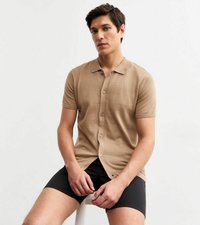 Camisa polo de punto beige de manga corta con dobladillo recto y cierre de botones, combinada con pantalones cortos negros. Textura suave, diseño clásico de cuello.