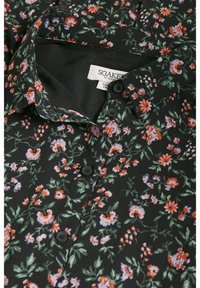 Czarna bluzka w kwiaty z zapięciem na guziki z przodu, krótkim kołnierzykiem oraz misternymi wzorami pomarańczowych, fioletowych i zielonych kwiatów na teksturowanym materiale.