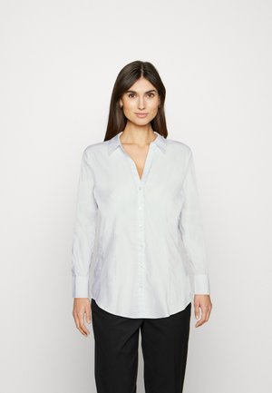 Witte lange mouw knopshirt met een kraag, met een gladde textuur en een getailleerd silhouet. Gecombineerd met zwarte broeken.