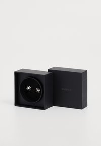 Srebrni uhani v obliki cvetov so razstavljeni v okroglem črnem žametnem notranjosti, postavljenem znotraj črne škatle z imenom blagovne znamke "MAPLE" na strani.