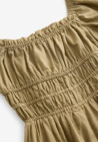 Olivi vihreä mekko, jossa on smokkibodice, korostaa kerättyä rakennetta ja elastisia olkapäitä. Pehmeä kangas, joka on virtaava muotoilu.