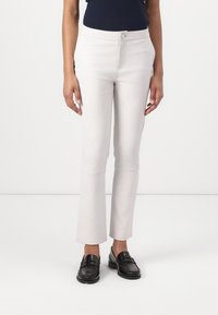 Ljust gråa figurnära byxor i bomullsblandning, med en framknäppning och något utsvängd nederkant. Bärs med svarta loafers.