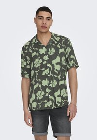 Grünes, blumiges Kurzarmhemd aus leichtem Stoff, mit einem knopffreien Design und weißen Knöpfen sowie einer lockeren Passform.