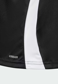 Svart sporttopp med en vit sidopanel, fuktavledande tyg märkt "AEROREADY", slät textur med precisa sömmar.