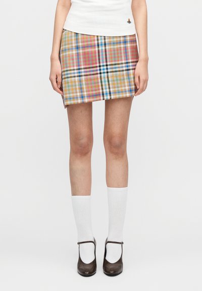 Jupe mini à carreaux en beige, rose, bleu et vert avec une texture lisse. Assortie à des chaussettes blanches montantes jusqu'aux genoux et des chaussures Mary Jane marron.