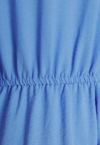 Himmelblauem Stoff mit weicher Textur, ausgestattet mit gerafftem Gummiband an der Taille für ein tailliertes Design. Glatte und fließende Drapierung.