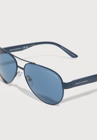 Σκούρα μπλε γυαλιά ηλίου τύπου αεροπόρου Armani Exchange με σκουρόχρωμους φακούς και εμφανές λογότυπο της μάρκας στα πλαινά και στο φακό, τοποθετημένα πάνω σε φωτεινή επιφάνεια.