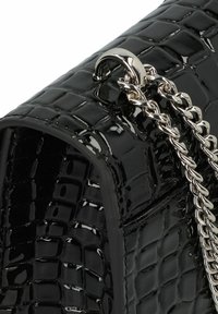 Borsa a mano in pelle sintetica nera con finitura lucida, caratterizzata da una texture a coccodrillo, dettagli in metallo argentato e una tracolla a catena, che enfatizza una forma rettangolare.