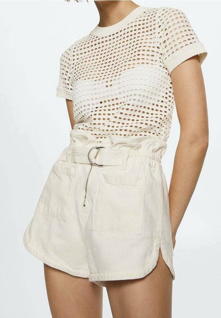 Femme portant un haut en maille beige à manches courtes et un short paperbag taille haute avec ceinture et fentes latérales sur fond clair.