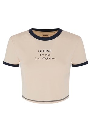 Camiseta de tiro corto y manga corta en color beige con ribete azul marino. Presenta un texto impreso que dice "GUESS Est. 1981 Los Ángeles" en la parte frontal. Textura suave.