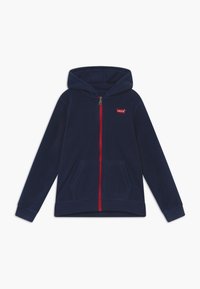 Granatowa polarowa bluza z kapturem z czerwoną zamkiem. Posiada przednią kieszeń i logo Levi's w kolorze czerwonym na lewej klatce piersiowej. Konstrukcja z kapturem.