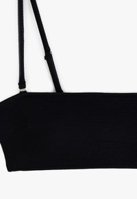 Zwarte bralette van textuurstof, brede band, verstelbare straps en een gladde afwerking. Geen zichtbare hardware of patronen.