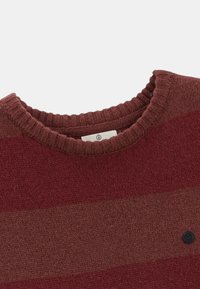 Pull en tricot bourgogne avec des rayures horizontales. Doté d'un col rond côtelé et d'un petit bouton logo noir à l'avant.