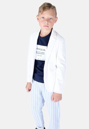 Hvid blazer over en marineblå t-shirt med grafisk tekst, parret med lyseblå og hvide stribede bukser. Glatte teksturer, struktureret pasform.