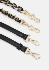 Due catene nere con ganci dorati e due cinture in pelle nera con ganci dorati su uno sfondo bianco.