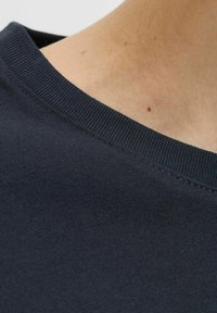 Navyblauwe katoenen T-shirt stof close-up, met een geribde halslijn en een gladde textuur met zichtbare stikdetails.