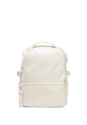 Square-shaped off-white backpack with top handle, multiple zippered compartments, and subtle embossed logo on front.