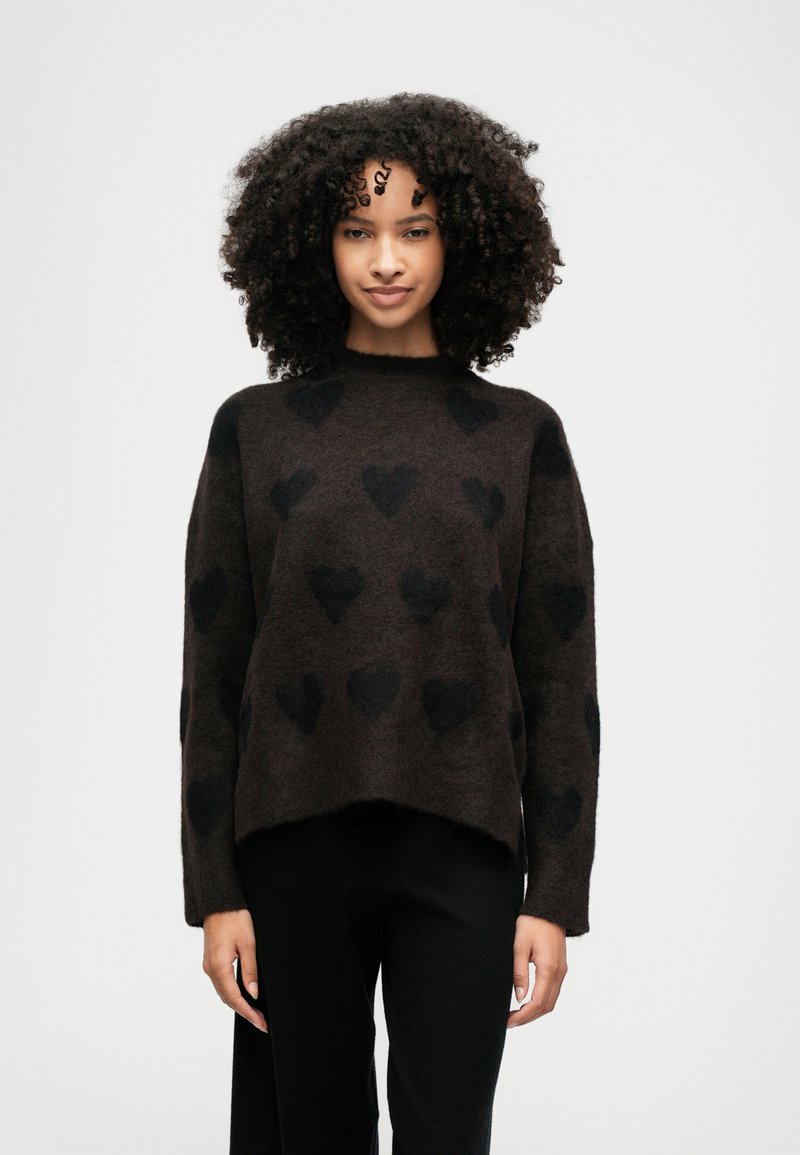 Καφέ πλεχτό πουλόβερ με μαύρα σχέδια καρδιάς, στρογγυλή λαιμόκοψη και χαλαρή εφαρμογή; μαλακή υφή με ελαφρώς μεγαλύτερο πίσω στρίφωμα.