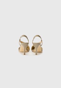 Beige high-heeled sandals with an ankle strap, smooth material, tapered heel, and subtle gold accents near the strap.