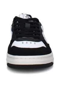 Sneaker bianco e nero con upper in suede, lacci neri e fori sulla punta. Presenta una suola intermedia bianca e una suola in gomma spessa.