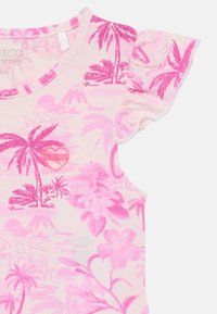 Różowa koszula z krótkim rękawem z tropikalnym wzorem palem i kwiatów, ozdobiona logo w kształcie serca. Miękka tkanina z falbanek na rękawach.