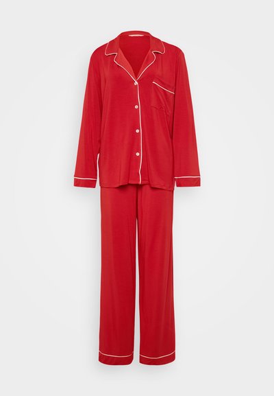 Red pajama set made of soft fabric; features white piping on collar, pocket, and cuffs; includes long-sleeve top and full-length pants.