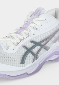 Λευκό και λεβάντας αθλητικό παπούτσι ASICS με επάνω μέρος από δίχτυ, λογότυπο στο πλάι και λευκά κορδόνια δεμένα σε φιόγκο.