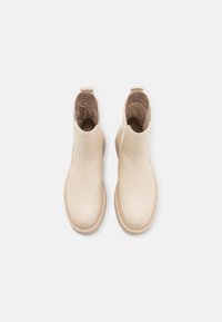 Bottines en cuir crème avec des panneaux latéraux élastiques, bout rond et détails cousus. Extérieur lisse et doublure intérieure douce.
