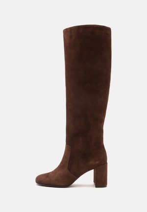 Bottes hautes en daim marron avec un bout arrondi et un talon bloc, vues de profil sur un fond clair uni.