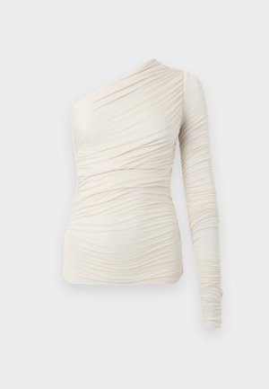 Asymmetrisk kremfarget topp laget av mykt stoff, med ett langt erme og rynkedetaljer over hele. Enkel, tettsittende design.