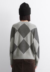 Grau-schwarzer Argyle-Muster-Pullover, gestrickt mit einer weichen Textur. Inklusive einer schwarzen gerippten Mütze. Wärmend und lässige Passform.