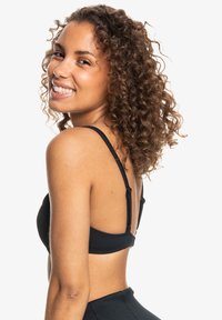 Svart ribbet bikini topp med justerbare stropper, med en glatt tekstur og et klassisk design, i kombinasjon med matchende bikiniunderdeler.