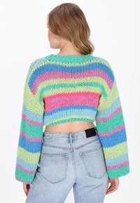 Virkat tröja med långa ärmar, iögonfallande randigt mönster i grönt, rosa, blått och lila. Kort design med öppen ryggdetalj.