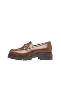 Loafer en cuir marron avec une boucle décorative, doté d'une semelle en caoutchouc noir épaisse et d'un détail de couture le long du bord.