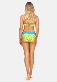 Zestaw bikini w tropikalny wzór w kolorze żółtym i niebieskim; top bandeau z regulowanymi ramiączkami; biodra zakryte dopasowanym niebieskim pasem; gładka tekstura.