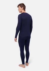 Marinblå termisk baslageruppsättning bestående av en långärmad topp och leggings. Slät textur med passande design, sömlös konstruktion och minimala detaljer.