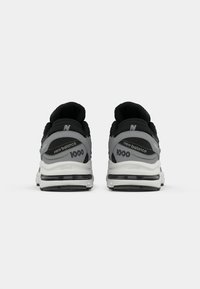 Pair of black and gray New Balance 1000 sneakers viewed from the back on a white background.