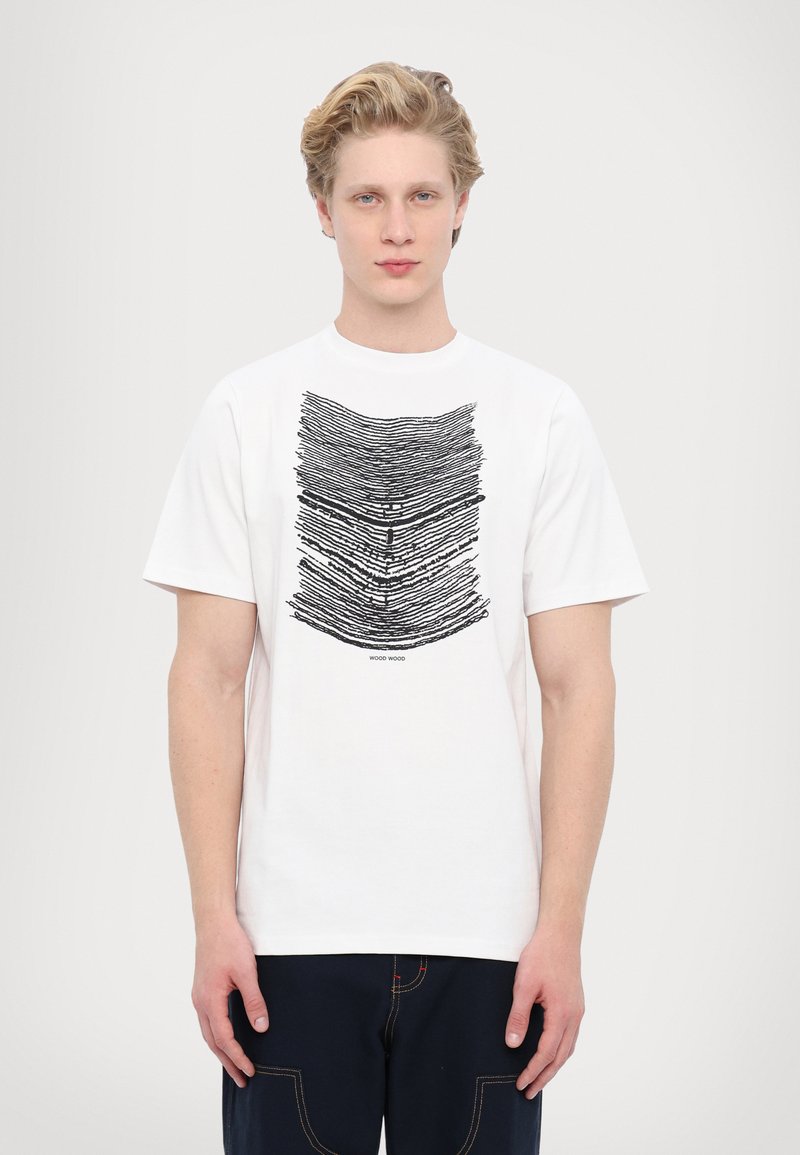 Balta kokvilnas t-krekls ar melnu abstraktu grafisko dizainu priekšpusē, apaļu kakla izgriezumu un īsām piedurknēm. Standarta piegrieztne.