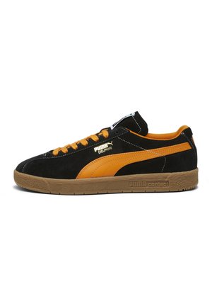 Baskets basses Puma en daim noir avec des bandes et lacets orange, semelle en gomme, et logo Puma Delphin blanc sur le côté.