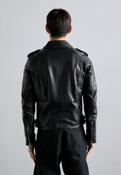 Giubbotto da motociclista in pelle nera con spalline e polsini con zip, caratterizzato da una texture liscia e dallo stile aderente.