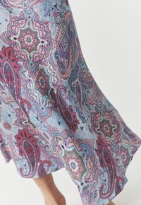 Robe en tissu à motifs paisley multicolores, avec des nuances de bleu, rose et rouge. Texture douce avec un design fluide et un ourlet inégal.