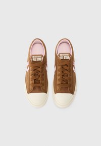 Brown canvas sneakers with pink accents, featuring a textured upper, round toe, and contrasting white rubber sole. All Star branding on tongue.