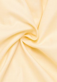 Struktureret stof i lys gul med et diagonalt mønster, der har en glat overflade og draperingsevne.