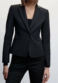 Černý blazer s klopovým límcem, zapínání na jeden knoflík a přiléhavým střihem. Texturovaná tkanina s bočními kapsami a dlouhými rukávy.